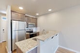 This two-story home in Twin Falls, Idaho offers a practical and modern layout spread across two floors. The main level features an inviting entrance that leads into a bright living room with wood-style flooring, and a well-equipped kitchen highlighted by rich dark wood cabinetry, granite countertops, stainless steel appliances, and a peninsula with bar seating — ideal for casual dining. A convenient half bathroom is also located on this floor. The main level is completed by a dedicated laundry area and access to a private patio, perfect for outdoor relaxation. Upstairs, two generously sized bedrooms are carpeted for comfort and filled with natural light through window treatments. The primary bedroom is a spacious retreat with its own closet. A hallway connects the upper-level spaces, which include two full bathrooms featuring clean white tub surrounds and granite-topped vanities with dark wood cabinetry consistent with the home's overall aesthetic. Three closets provide ample storage throughout. Neutral warm-toned walls, recessed lighting, and wood-style flooring on the main level create a cohesive, clean ambiance that flows seamlessly from room to room.