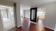 Located at 100 W Chestnut St in Chicago's vibrant Near North Side neighborhood, this well-appointed residence offers a thoughtfully designed single-floor layout. The open living and dining area is highlighted by rich, dark hardwood flooring and neutral gray walls that create a clean, contemporary aesthetic. Multiple windows allow natural light to fill the space while framing striking views of the Chicago skyline and surrounding cityscape.

The kitchen is equipped with warm oak cabinetry, granite-style countertops, a stainless steel refrigerator, and an electric range, providing a functional space for everyday cooking. A peninsula-style counter connects the kitchen to the main living area, enhancing the open feel of the layout.

The bedrooms feature plush wall-to-wall carpeting and neutral tones, offering a comfortable and quiet retreat. One bedroom benefits from a window with direct city views, adding an urban character to the private spaces.

Two full bathrooms serve the residence, each featuring a tub-shower combination, wood vanity cabinetry with marble-toned countertops, mirrored medicine cabinets, and tile flooring. One bathroom features warm earth-toned tile surrounding the tub, while the second presents a clean, all-white finish. Together, the spaces offer a practical and cohesive living environment in the heart of Chicago.