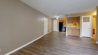 Located at 4008 Williamsburg Village Dr in Jackson, Tennessee, this single-floor unit offers a functional and comfortable layout designed for everyday living. The open-concept living and dining area is finished with durable wood-look hardwood-style flooring and neutral warm-toned walls, creating a welcoming atmosphere throughout. A sliding glass door fitted with vertical blinds allows natural light to fill the living space while providing access to the outdoors. The kitchen is positioned adjacent to the living area and features warm oak cabinetry with ample storage, light countertops, a double-basin sink, and a full suite of black appliances including a refrigerator, electric range, over-the-range microwave, and dishwasher. The bedroom is generously sized with plush wall-to-wall carpeting, a window with blinds offering natural light, and a textured ceiling. The full bathroom is appointed with wood-look vinyl flooring, an oak vanity with a single sink and built-in shelving, a toilet, and a full tub-shower combination. Warm beige walls and white trim are consistent throughout the unit, lending a cohesive and clean aesthetic to the overall space.