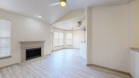 This well-appointed 4-bedroom, 2-bathroom home offers a thoughtfully designed layout across a single floor, making excellent use of its generous square footage. The open-concept living room is a standout, featuring soaring vaulted ceilings, a ceiling fan, a classic fireplace, and light wood-style flooring that flows throughout the main living areas. Large windows fitted with blinds fill the space with natural light, while a glass door opens directly onto a private balcony, extending the living space outdoors. The dining area is defined by a tray ceiling with built-in track lighting, adding architectural interest. The kitchen is well-equipped with rich dark wood cabinetry, granite countertops, a subway tile backsplash, stainless steel appliances including a range, microwave, and dishwasher, and matching light wood-style flooring. Each of the four bedrooms is carpeted and includes a ceiling fan and windows for natural light. The primary bedroom is a comfortable retreat with access to a full en-suite bathroom, which features dual granite-topped vanities, dark wood cabinetry, and a walk-in closet with built-in wire shelving. A second walk-in closet, a dedicated laundry area, a hallway, and a staircase complete this home's functional and inviting floor plan.