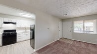 Located at 1699 Shanley Dr in Columbus, Ohio, this single-floor unit offers a practical and well-organized layout designed for comfortable everyday living. The kitchen is a standout functional space, outfitted with crisp white cabinetry featuring brushed nickel hardware, light wood-look vinyl flooring, a stainless steel sink with a modern pull-down faucet, and a full suite of black appliances including a gas range, dishwasher, and refrigerator. A ventilation hood above the range and ample upper and lower cabinet storage add to its utility. The living area is generously sized with neutral-toned carpet, light gray walls, and a textured ceiling, creating a bright and open feel. Natural light filters in through windows fitted with blinds. The bedrooms continue the carpeted flooring and neutral palette, with one bedroom featuring a wide open closet with double hanging rods, ideal for storage. The bathrooms are cleanly finished — one includes a tub-shower combination and a white vanity, while the other offers a vanity with a mirror and overhead lighting. Throughout the unit, consistent neutral tones and light finishes contribute to a clean, move-in-ready atmosphere.