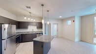 Located at 455 South Recker Road in Gilbert, AZ, this well-appointed one-bedroom, one-bathroom unit offers a thoughtfully designed single-floor layout. The open-concept kitchen is a standout feature, boasting dark espresso cabinetry, granite countertops, a central island with pendant lighting, and a full suite of stainless steel appliances including a refrigerator, range, microwave, and dishwasher. Track lighting and tile-style flooring add a modern, polished touch throughout the main living area, which is bright and open with a ceiling fan overhead and windows allowing natural light to fill the space. A private entrance door is accessible directly from the living area. The bedroom offers plush carpeting, a ceiling fan, and a sliding glass door leading to an outdoor area, providing a comfortable and airy retreat. The spacious walk-in closet features multiple hanging rods and built-in shelving for ample storage. The bathroom includes dark cabinetry vanity with a sink, complemented by the same tile-style flooring found throughout. A dedicated in-unit laundry room with washer and dryer and overhead shelving adds everyday convenience to this efficiently designed Gilbert residence.