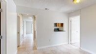 Located in Sun Valley Village in Altamonte Springs, Florida, this single-story, 3-bedroom, 2-bathroom home offers a functional and comfortable layout. The open living room is a standout feature, showcasing light wood-style flooring, a textured ceiling, a ceiling fan, and a tile-surround fireplace that serves as a focal point. Large sliding glass doors bathe the space in natural light and provide views of the surrounding greenery. The kitchen is efficiently designed with warm wood cabinetry, dark granite-style countertops, a pass-through window to the living area, and black appliances including a range, microwave, and refrigerator. Tile flooring runs throughout the kitchen and hallway areas. The bedrooms feature the same light wood-style flooring found in the living room, with multiple rooms offering sliding glass doors that open to outdoor views. The spacious primary bedroom includes a dedicated walk-in closet with wire shelving. The bathrooms are appointed with dark-topped vanities, wood cabinetry, full mirrors, and tile flooring, with a shower-tub combo in the shared bath. A connecting hallway ties all rooms together, creating a cohesive and easy-to-navigate floor plan throughout the home.