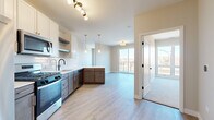 Located at 101 S Main St in Lombard, Illinois, this well-appointed single-floor residence offers a thoughtfully designed open-concept layout with contemporary finishes throughout. The kitchen is a standout feature, showcasing a two-tone cabinet design with crisp white uppers and warm wood-toned lower cabinets, complemented by light quartz countertops, a subway tile backsplash, stainless steel Whirlpool appliances including a gas range, microwave, and dishwasher, and elegant pendant lighting. The kitchen flows seamlessly into the living and dining area, which is finished with light wood-style flooring and accented by a sliding glass door that opens onto a private balcony overlooking the surrounding neighborhood. The bedrooms are carpeted for comfort and feature large windows that invite abundant natural light and views of the streetscape below. The bathroom is outfitted with a sleek walk-in shower enclosed by a frameless sliding glass door with matte black hardware. A dedicated walk-in closet with built-in shelving and hanging rods provides generous storage. The unit also includes an in-unit laundry area with a full-size Whirlpool washer and dryer. Clean panel-style interior doors with black hardware add a modern touch throughout the residence.