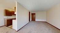 Located at 805 Rilla Rd in Saint Cloud, Minnesota, this single-floor unit offers a practical and well-organized layout throughout. The open living area features neutral-toned carpet, textured ceilings, and warm wood baseboards that carry consistently through the space. A solid wood entry door welcomes residents into the generously sized living room, which flows seamlessly from the kitchen via a half-wall partition.

The galley-style kitchen is equipped with warm wood cabinetry extending to the upper and lower walls, a double sink, electric range, refrigerator, and tile flooring that adds durability to the space. A dedicated storage closet is accessible directly from the kitchen.

The bedroom is spacious and carpeted, featuring a full wall of sliding wood-panel closet doors for ample storage. A wall-mounted air conditioning unit and a large sliding glass door with vertical blinds flood the room with natural light and provide access to an outdoor view. Baseboard heating runs along the perimeter for efficient climate control.

The bathroom is clean and functional, featuring a full tub-shower combo with built-in shelving, a wood-trimmed vanity, and tasteful large-format tile flooring. Throughout the unit, the consistent use of warm wood tones and neutral wall colors creates a cohesive and practical living environment.
