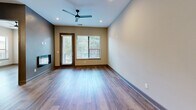 Located at 301 Nichols St in Fort Worth, Texas, this well-appointed two-bedroom, one-bathroom residence offers a thoughtfully designed single-level layout with modern finishes throughout. Wide-plank wood-look flooring flows seamlessly across every room, lending a warm and cohesive aesthetic to the entire space.

The open-concept kitchen and living area serves as the heart of the home. The kitchen is outfitted with white cabinetry, a subway tile backsplash, stainless steel appliances including a refrigerator, dishwasher, range with hood, and built-in microwave — all illuminated by recessed lighting. The adjoining living room features a sleek wall-mounted electric fireplace, a ceiling fan, and a glass-panel exterior door flanked by windows that bring in generous natural light and views of surrounding greenery.

Both bedrooms are bright and comfortable, each with large windows dressed in horizontal blinds. The primary bedroom offers a mirrored sliding-door closet with built-in shelving, maximizing storage. The shared bathroom features a wide dual-sink vanity with white cabinetry, brushed nickel hardware, and a full-width mirror with overhead lighting. A dedicated laundry area houses a stacked full-size washer and dryer. The hallway connects all rooms efficiently, completing this clean and functional layout.