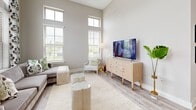 Located at Cay Plaza in Savannah, Georgia, this single-story residence offers two bedrooms and two bathrooms within a thoughtfully designed floor plan. The interior is defined by notably high ceilings and light-toned luxury vinyl plank flooring that flows throughout, creating a cohesive and airy aesthetic.

The entryway sets an inviting tone with soaring ceilings and clerestory windows that draw in natural light. The open-concept kitchen is a standout feature, equipped with stainless steel appliances, a gas range, dark granite countertops, sleek gray cabinetry, a central island with pendant lighting above, and direct access to an outdoor balcony.

The living room benefits from floor-to-ceiling windows with transom panels above, filling the space with generous daylight and offering outdoor views. The primary bedroom features French door balcony access and ample room for a full suite of furniture. The second bedroom also enjoys large windows with natural light. Both bathrooms are finished with marble-style tile, gray vanities with dark countertops, and modern fixtures — one featuring a walk-in glass shower, the other a full soaking tub. A functional hallway connects all areas efficiently.