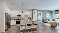 Located at 355 Broad St in Newark, NJ, this well-appointed 2-bedroom, 2-bathroom residence offers a thoughtfully designed single-floor layout with a clean, contemporary aesthetic. The open-concept living area anchors the home, where the kitchen, dining, and living spaces flow seamlessly together. The kitchen is outfitted with white shaker cabinetry, stainless steel appliances, a mosaic tile backsplash, and a dark-topped island with pendant lighting above — ideal for both meal prep and casual dining. Wide-plank hardwood flooring runs throughout, complementing the neutral color palette accented by soft sage green walls in the living area. The living room benefits from large windows and a sliding glass door that opens to a private balcony with outdoor views. The spacious primary bedroom features its own balcony access, a dedicated closet, and a private en-suite bathroom with a glass-enclosed shower and modern vanity. The second bedroom is generously sized with its own closet, while the second bathroom includes a full soaking tub with large-format tile surround and matte black fixtures. Recessed lighting, modern hardware, and clean architectural lines create a cohesive, refined ambiance throughout the home.