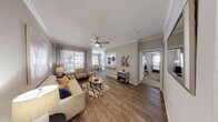 This single-floor residence offers a thoughtfully designed open-concept layout that seamlessly connects the living, dining, and kitchen areas. The living room is finished with rich hardwood-style flooring, crown molding, and a ceiling fan, creating a comfortable and polished atmosphere. Natural light flows in through multiple windows dressed with elegant curtains, enhancing the warm, neutral color palette that runs throughout the home.

The kitchen is equipped with stainless steel appliances, including a range, over-the-range microwave, and refrigerator. White cabinetry pairs cleanly with granite countertops and a classic subway tile backsplash, offering both style and functionality. A pass-through counter opens to the dining and living areas, reinforcing the open flow of the space.

The residence includes multiple bedrooms, each featuring plush carpeting, ceiling fans, and generous natural light. The primary bedroom includes a walk-in closet and direct access to a private en-suite bathroom. Both bathrooms are finished with granite-topped white vanities, large mirrors with bright vanity lighting, and tile flooring. The primary bath features a full soaking tub with shower, while the secondary bath offers a refined, efficient layout.

Overall, the space presents a cohesive, modern aesthetic with quality finishes and a functional, comfortable design throughout.