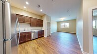 Located at 204 N Fourth St in DeKalb, IL, this single-floor unit offers a well-designed layout with consistent hardwood-style flooring throughout. The kitchen is a standout feature, equipped with rich dark wood cabinetry, granite-style countertops, and a full suite of stainless steel appliances including a refrigerator, range, microwave, dishwasher, and sink. Recessed lighting illuminates the kitchen area, which flows seamlessly into an open living space bathed in natural light from a large window overlooking the surrounding streetscape.

The living area provides generous open space with a flush-mount light fixture and neutral warm-toned walls, creating a bright and welcoming ambiance. A dedicated bedroom features hardwood-style flooring, a window with outdoor views, and a built-in closet with a rod and shelving for organized storage.

The bathroom is finished with large-format white marble-style tile on both the floors and walls, complemented by a dark-framed mirror, a wood vanity with granite-style countertop, and a walk-in shower. A dedicated in-unit laundry nook houses a stacked Whirlpool washer and dryer, adding practical convenience to the space.