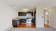 Located at 1727 Locust Pl in Schaumburg, IL, this efficiently designed single-floor unit makes excellent use of its intimate footprint. The open-plan kitchen and living area form the heart of the space, where warm hardwood flooring in the kitchen transitions seamlessly into plush carpeting in the living area. The kitchen is well-equipped with dark espresso cabinetry, a subway tile backsplash, light countertops, and a full suite of stainless steel appliances — including a range, over-the-range microwave, refrigerator, and dishwasher. A double-basin sink with a modern faucet completes the functional layout. The living area is bright and open, benefiting from a large sliding glass door dressed with vertical blinds that invites generous natural light and offers outdoor views of surrounding greenery. A wall-mounted HVAC unit and baseboard heating ensure year-round comfort. The bathroom features clean white tile, a tub-shower combination, and a classic tiled floor, maintaining a crisp and functional aesthetic. A dedicated closet provides practical storage. Neutral wall tones and consistent finishes throughout create a cohesive and welcoming atmosphere well-suited for everyday living.
