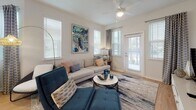 Located at 6426 Brook Village in Bradenton, Florida, this single-story residence offers a well-designed open-concept layout that seamlessly connects the kitchen, dining, and living areas. Light wood-style flooring flows throughout the main living spaces, complemented by neutral walls and an abundance of natural light streaming through multiple windows fitted with blinds and patterned curtains.

The kitchen is a standout feature, equipped with white shaker cabinetry, a subway tile backsplash, stainless steel appliances including a refrigerator, range, and microwave, and a central island with a undermount sink and pendant lighting above. The island provides additional seating and serves as a natural divider between the kitchen and the open dining area.

The living room is generously proportioned, featuring a ceiling fan, multiple windows offering outdoor views, and a private exterior door. The bedrooms offer plush carpeting, natural light, and well-proportioned layouts. One bedroom features a calming blue accent wall, while another presents a soft neutral palette. The bathroom includes wood-toned cabinetry, light flooring, and a tiled shower. A dedicated laundry room with full-size washer and dryer completes this functional and stylish residence.