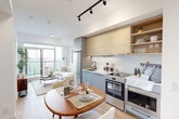 Located at Eastern Ave in Toronto's East End neighbourhood, this one-bedroom, one-bathroom unit offers a thoughtfully designed open-concept layout across a single floor. Light hardwood flooring runs throughout, complementing the bright, neutral palette that defines the space.

The kitchen is outfitted with two-tone cabinetry — soft blue lower cabinets paired with natural wood uppers and open shelving — along with stainless steel appliances including a full-size refrigerator, electric range, and built-in microwave. A dedicated closet nook houses a stacked in-suite washer and dryer, adding everyday convenience.

The living area flows seamlessly from the kitchen and dining space, anchored by large floor-to-ceiling sliding glass doors that open onto a private balcony with open city views, filling the room with natural light.

The bedroom is a calm, compact retreat with a large window overlooking the balcony greenery, finished in crisp white walls and warm hardwood flooring. A dedicated closet provides practical storage.

The bathroom features large-format white tile flooring, a full soaker tub with shower, and a wood-accented vanity with matte black fixtures, creating a clean and cohesive finish throughout.