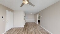 This single-story, one-bedroom, one-bathroom unit at 7500 Southside Blvd in Jacksonville, Florida offers a thoughtfully arranged floor plan that maximizes its compact footprint. The open living area features wood-look vinyl plank flooring, neutral warm-beige walls, a textured ceiling, and a ceiling fan with integrated lighting. A door with slatted blinds allows natural light to filter into the space, creating a bright and welcoming atmosphere.

The kitchen is equipped with dark espresso-toned cabinetry, light quartz countertops, subway tile backsplash, and stainless steel appliances including a full-size refrigerator. A hallway connects the main living area to the private bedroom, which features plush carpeting, a ceiling fan, a window with blinds, and access to a walk-in closet outfitted with multi-tiered wire shelving.

The bathroom includes a dark-toned vanity with a white quartz countertop, a framed mirror, brushed nickel fixtures, and a full tub-shower combination. The unit also includes a dedicated laundry area, adding everyday convenience. Throughout, the consistent use of neutral tones and modern finishes creates a cohesive and functional living environment.
