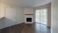 This single-story residence at 100 Knolls Pl in Nashville, TN offers a well-organized layout with a blend of functional and comfortable living spaces. The living room serves as a central highlight, featuring a classic white brick corner fireplace with a wood mantel and rich, dark hardwood-style flooring. A full-length sliding glass door with vertical blinds floods the space with natural light while providing outdoor access.

The kitchen is equipped with stainless steel appliances, including a full-size refrigerator, microwave, and dishwasher, complemented by granite-style countertops and white cabinetry. A half-wall peninsula separates the kitchen from the adjacent living and dining area, creating an open, connected feel. Hardwood-style flooring continues throughout the kitchen and main living areas.

A dedicated laundry area with a stacked washer and dryer unit is conveniently accessible from the main hallway. The bathroom features wood-style flooring, a tub-shower combination with tiled surround, and an above-toilet storage cabinet. The bedroom is carpeted for comfort, includes a ceiling fan with lighting, and benefits from a window that allows ample natural light and outdoor views. Overall, the space presents a clean, neutral palette throughout.