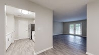Located at 300 Carpenter Dr in Sandy Springs, GA, this single-floor unit offers a thoughtfully updated interior with a clean, modern aesthetic throughout. The main living area is generously sized, showcasing durable gray-toned luxury vinyl plank flooring, neutral warm-gray walls, crisp white trim, and a textured ceiling. A set of French doors floods the space with natural light and provides access to the outdoors, enhancing the open and airy feel of the room. A louvered closet door adds a classic design touch to the living space. The kitchen features white shaker-style cabinetry with sleek bar-pull hardware, light stone countertops, a subway tile backsplash, and stainless steel appliances, including a full-size refrigerator. The bedrooms are finished with plush neutral carpeting, and one bedroom includes a ceiling fan with light fixture and a window with outdoor views. A spacious walk-in closet with wire shelving provides ample storage. The bathroom is well-appointed with a white vanity, stone countertop, undermount sink, pendant lighting, a large mirror, and a tub-shower combination. Additional rooms offer louvered closet storage and flexible layout options, rounding out this well-maintained, move-in-ready unit.