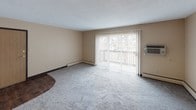 This 1-bedroom, 1-bathroom unit is thoughtfully laid out across a single floor, making efficient use of its compact footprint. The living room serves as the heart of the unit, featuring plush wall-to-wall carpeting, neutral beige walls, and a sliding glass door that opens to a private balcony — allowing natural light to fill the space while providing a pleasant outdoor view. Baseboard heating runs along the perimeter, and a ceiling-mounted light fixture adds overhead illumination.

The kitchen is finished with rich, dark wood cabinetry, dark granite-style countertops, a double-basin stainless steel sink, and durable hardwood-style flooring. Ample upper and lower cabinet storage makes the kitchen practical and functional.

The bedroom is a comfortable retreat with soft carpeting, warm neutral tones, and two windows that bring in natural light and views of the surrounding neighborhood. Baseboard heating keeps the room comfortable year-round.

The full bathroom is clean and functional, featuring a tub/shower combination, a wood-framed vanity with a granite-style countertop, overhead cabinetry for storage, and a mirror. Hardwood-style flooring completes the space with a cohesive, tidy look. Overall, this unit offers a straightforward and practical living environment.