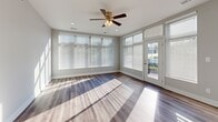 This thoughtfully designed single-floor residence combines contemporary finishes with a functional layout, creating a bright and welcoming living environment throughout. The open-concept kitchen is a standout feature, showcasing rich dark-stained cabinetry, stainless steel appliances including a range, microwave, and dishwasher, and crisp light-colored countertops. A central island with a sink adds both prep space and visual appeal, while recessed lighting and large windows bathe the area in natural light. The kitchen flows seamlessly into the main living area, which features durable wood-style flooring and an abundance of natural light streaming through generously sized windows, creating a warm and airy atmosphere. A ceiling fan overhead adds both style and comfort to the living space, which also provides direct access to an outdoor area through glass-paneled doors. The bedroom is carpeted for comfort and includes a well-organized reach-in closet with built-in shelving, offering ample storage. An additional walk-in closet with tiered shelving provides even more organizational capacity. The full bathroom is cleanly appointed with a tub-shower combination, a dark-cabineted vanity, and wood-style flooring. A dedicated in-unit laundry area with a full-size washer and dryer completes this practical and polished residence.