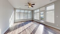 This thoughtfully designed single-floor residence combines contemporary finishes with a functional layout, creating a bright and welcoming living environment throughout. The open-concept kitchen is a standout feature, showcasing rich dark-stained cabinetry, stainless steel appliances including a range, microwave, and dishwasher, and crisp light-colored countertops. A central island with a sink adds both prep space and visual appeal, while recessed lighting and large windows bathe the area in natural light. The kitchen flows seamlessly into the main living area, which features durable wood-style flooring and an abundance of natural light streaming through generously sized windows, creating a warm and airy atmosphere. A ceiling fan overhead adds both style and comfort to the living space, which also provides direct access to an outdoor area through glass-paneled doors. The bedroom is carpeted for comfort and includes a well-organized reach-in closet with built-in shelving, offering ample storage. An additional walk-in closet with tiered shelving provides even more organizational capacity. The full bathroom is cleanly appointed with a tub-shower combination, a dark-cabineted vanity, and wood-style flooring. A dedicated in-unit laundry area with a full-size washer and dryer completes this practical and polished residence.