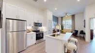 Located at 75 S 600 W in Salt Lake City, UT, this thoughtfully designed one-bedroom, one-bathroom residence offers a bright and contemporary living experience across a single floor. The open-concept layout connects the kitchen, dining, and living areas seamlessly, maximizing the efficient use of space.

The kitchen is a standout feature, outfitted with stainless steel appliances including a refrigerator, electric range, and over-the-range microwave. Crisp white shaker cabinetry reaches toward the ceiling, providing ample storage, while a peninsula with a undermount sink and white quartz-style countertops offers additional prep space and casual seating.

Light wood-style flooring runs throughout the main living areas, complementing the clean white walls and recessed lighting. The living room features a striking accent wall in a muted blue-gray tone, large windows with floor-to-ceiling drapes, and a ceiling fan, creating a comfortable and stylish retreat.

The bedroom is generously proportioned, featuring large windows that invite natural light and views of the outdoors. The bathroom includes a single-sink vanity with white cabinetry, a tub-shower combination with tile surround, and wood-style flooring. A dedicated closet completes the functional layout of this well-appointed residence.