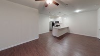 This single-floor residence offers a clean, modern design with a thoughtful layout that maximizes both comfort and functionality. The open-concept living and dining area is anchored by rich, dark hardwood-style flooring that extends throughout the main living spaces, complemented by neutral white walls and a ceiling fan with integrated lighting. A sliding glass door floods the living area with natural light and provides convenient access to the outdoors.

The kitchen is a standout feature, showcasing a large peninsula with a granite countertop and an integrated sink, illuminated by stylish pendant lights. White shaker-style cabinetry lines the walls, offering ample storage, while stainless steel appliances — including a refrigerator, range, over-the-range microwave, and dishwasher — complete the space. A subway tile backsplash adds a refined finishing touch.

The bedrooms are carpeted for added comfort, each equipped with a ceiling fan and ample natural light from windows fitted with blinds. The bathroom maintains the same high-quality finishes found throughout the unit, featuring a granite-topped white vanity, a framed mirror, and hardwood-style flooring. Clean lines and a neutral palette create a cohesive, move-in-ready living environment throughout the entire space.