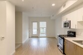 Located at 868 S Fifth St in San Jose, CA, this thoughtfully designed one-bedroom, one-bathroom unit offers a clean, modern aesthetic throughout. The open-concept living and kitchen area is anchored by light wood-style flooring that extends seamlessly through the main living space, creating a bright and airy atmosphere enhanced by recessed lighting and large windows that invite natural light. A sliding glass door leads to a private balcony, extending the living area outdoors.

The kitchen is well-appointed with a full suite of stainless steel appliances—including a refrigerator, range, microwave, and dishwasher—complemented by two-tone cabinetry featuring warm wood lower cabinets and crisp white uppers, paired with light countertops for a contemporary finish.

The bedroom offers a comfortable, carpeted retreat with a generous sliding-door closet and ample wall space for flexible furniture arrangements. The bathroom is finished with wood-toned cabinetry, a white countertop vanity, a soaking tub with tiled surround, and accessibility-friendly grab bars. The clean white walls and neutral palette throughout the unit create a cohesive, move-in-ready living environment well-suited for modern urban living in the heart of San Jose.