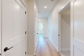 Located in Denver's vibrant 80220 neighborhood, this single-floor, 2-bedroom, 1-bathroom residence offers a thoughtfully designed layout with modern finishes throughout. Light hardwood floors flow seamlessly across the living areas, complementing the neutral, warm-toned walls and crisp white trim with matte black hardware accents visible throughout the hallways and doors.

The open-concept kitchen, dining, and living area serves as the heart of the home, featuring white flat-panel cabinetry extending to the ceiling, a herringbone tile backsplash, stainless steel appliances, and a large center island with a clean white countertop — ideal for both cooking and entertaining. Recessed lighting brightens the space, which also benefits from generous natural light.

The spacious primary bedroom is filled with natural light through multiple large windows offering views of the surrounding Denver neighborhood and mature trees. The second bedroom also features hardwood floors and ample natural light. Four closets provide excellent storage throughout.

The bathroom is designed with accessibility in mind, featuring grab bars, large-format white tile flooring, a soaking tub with a tiled surround, and a clean, open layout. A dedicated laundry area and pantry add everyday convenience. The bright, wide hallway connects all rooms with a polished, modern aesthetic.