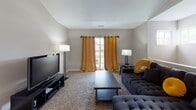 This single-floor home offers a practical and comfortable layout with multiple distinct living spaces. The living room features soft carpeting, vaulted ceilings, and a sliding door framed by warm gold curtains that invite natural light and provide access to an outdoor patio. The galley-style kitchen is outfitted with oak cabinetry, dark granite countertops, tile flooring, and a louvered pantry door for added storage. Adjacent to the kitchen, the dining area is finished with tile flooring and neutral walls accented by framed artwork, creating a relaxed and welcoming atmosphere. The home includes multiple carpeted bedrooms, each featuring large windows with blinds that allow ample natural light. The bathrooms are consistently appointed with oak vanities, dark granite countertops, tile flooring, and shower-tub combinations. The overall design is neutral and understated throughout, with warm beige and gray tones creating a cohesive aesthetic. Each room is thoughtfully proportioned, offering functional space while maintaining a cozy residential feel. This home is well-suited for everyday living with its blend of practical finishes and comfortable spaces across a single level.