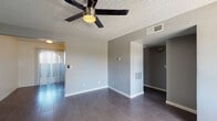 This single-floor unit offers a clean, modern aesthetic defined by a cohesive neutral gray color scheme, white baseboards, and durable tile flooring throughout. The open living area is spacious and well-lit, featuring a ceiling fan with integrated lighting, vertical blind-covered windows that allow natural light to filter in, and a textured ceiling that adds subtle visual interest. A secondary living or flex space mirrors this layout, also equipped with a ceiling fan and tile flooring, providing versatility for various uses.

The kitchen is efficiently designed in an L-shaped configuration, outfitting with gray cabinetry on both upper and lower sections, white countertops, a double-basin stainless steel sink, and a black dishwasher. A dedicated HVAC vent overhead ensures year-round comfort in the space.

The bedrooms are generously sized, each featuring dark tile flooring, textured ceilings, and windows with vertical blinds that frame outdoor views of surrounding greenery. The rooms offer a calm, neutral environment well-suited for rest or a home office setup.

The bathroom is thoughtfully appointed with a tiled tub-shower combo, a single-sink vanity with gray cabinetry and a white countertop, a large mirror, and wood-look tile flooring. The overall unit presents a well-maintained, move-in ready interior with a consistent and functional design throughout.