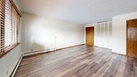 Located at 219 3rd Ave SW in Forest Lake, Minnesota, this two-bedroom, one-bathroom unit offers a practical and comfortable single-floor layout. The living room is bright and open, featuring hardwood-style flooring, a textured ceiling, and a wide window with wood-trimmed blinds that frames views of the surrounding neighborhood. Baseboard heating runs throughout the main living areas, ensuring consistent warmth during Minnesota winters.

The kitchen is efficiently designed with white cabinetry, granite-look countertops, stainless steel refrigerator and range, an under-cabinet range hood, and a ceiling fan with light. A window above the dining area brings in additional natural light, and a wall-mounted A/C unit provides seasonal climate control.

Both bedrooms are well-sized and carpeted for comfort. The primary bedroom benefits from dual windows with wood-trimmed blinds and a ceiling fan, while both rooms feature generous closet space — including large louvered bifold closet doors. The unit boasts an impressive six closets in total, offering exceptional storage throughout.

The full bathroom is cleanly finished with white tile surrounding the tub/shower combination, mosaic tile flooring, and classic fixtures. Hardwood-style flooring continues through the hallway, tying the space together cohesively.