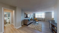 Located at Dayton Towers in Dayton, Ohio, this single-floor residence offers a well-designed layout with a thoughtful blend of modern finishes and functional living spaces. The expansive living room serves as the heart of the home, featuring light wood-style flooring, neutral-toned walls, and large windows that invite an abundance of natural light. The open layout comfortably accommodates both a seating and dining area, with a ceiling fan adding to the room's practicality. The galley-style kitchen is outfitted with rich dark wood cabinetry, crisp white countertops, a stainless steel sink, and black appliances including a gas range, dishwasher, and refrigerator. A window at the end of the kitchen provides additional natural light and a connection to the living space beyond. The bedroom is a serene retreat, carpeted for comfort and featuring a generous mirrored sliding-door closet that enhances the sense of space, along with a window that fills the room with soft natural light. The full bathroom includes a tiled tub-shower combination, a wood-toned vanity with a white countertop, and a large wall mirror with integrated lighting — all finished in a clean, classic style. Throughout the residence, consistent design choices create a cohesive and inviting atmosphere.