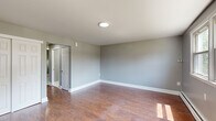 Located at 71 Lakeland Rd in Blackwood, NJ, this well-maintained 2-bedroom, 1-bathroom home offers a practical and comfortable single-floor layout. The interior is finished with a neutral gray color palette throughout, creating a clean and cohesive aesthetic. The spacious primary bedroom features rich hardwood flooring, a large multi-pane window that draws in ample natural light, and views of the surrounding greenery. The second bedroom is carpeted for added comfort and includes a built-in closet with double doors and its own window overlooking the outdoors. The kitchen is a functional highlight of the home, outfitted with deep-toned hardwood cabinetry, a classic white subway tile backsplash, light countertops, a gas range, a refrigerator, and a stainless steel sink. White tile flooring in the kitchen adds a crisp contrast to the warm cabinetry. The bathroom is neatly appointed with white subway tile lining the tub surround, accented by a decorative mosaic border, white tile flooring, and a clean, minimalist finish. The main living area features hardwood floors, baseboard heating, and generous windows that fill the space with natural light, completing this efficient and inviting home.