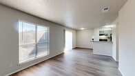 This single-floor residence offers a thoughtfully arranged 2-bedroom, 2-bathroom layout that maximizes every square foot. The open-concept living and kitchen area serves as the heart of the home, featuring durable wood-style laminate flooring, neutral gray walls, and a textured ceiling that adds dimension overhead. Large windows dressed with horizontal blinds flood the living space with natural light, while a sliding glass door provides additional brightness and access to the outdoors.

The kitchen is defined by a peninsula with a granite-style countertop, dark cabinetry, black appliances, and a stainless steel sink — combining functionality with a clean, modern aesthetic.

Both bedrooms are carpeted for comfort and include ceiling fans with light fixtures. The spacious primary bedroom features a walk-in closet and direct access to its own bathroom, offering a private retreat. The second bedroom also benefits from natural light through a dedicated window.

The two bathrooms are finished with white vanities, wood-style flooring, and tiled shower/tub combinations, maintaining a crisp and clean look throughout. A hallway connects the bedrooms to the main living areas, with additional closet storage available to maximize organization within this efficiently designed home.