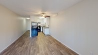 Located at 1501 E Grand Ave in Escondido, California, this single-floor unit offers a practical and well-appointed layout designed for comfortable everyday living. The main living area is open and airy, finished with durable wood-style plank flooring that extends throughout the space. A ceiling fan provides year-round comfort, while a sliding glass door opens to an outdoor area, allowing natural light to flow in alongside views of surrounding greenery. A separate window further brightens the room.

The kitchen is efficiently designed with crisp white cabinetry offering ample storage, gray countertops, a stainless steel sink, and black appliances including a refrigerator, range, and dishwasher. A flush-mount ceiling light illuminates the workspace clearly.

The bathroom is clean and functional, featuring a full tub and shower combination with a curved curtain rod, a toilet, and a vanity with a single-basin sink set into a gray countertop. A wall-mounted mirror and overhead lighting complete the space, with a small window providing natural ventilation.

Neutral wall tones and textured ceilings are consistent throughout, lending the unit a cohesive and understated aesthetic. The overall layout is straightforward and move-in ready, making it a practical option in the Escondido area.