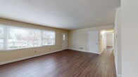 Located at 2326 Chalet Gardens Rd in Fitchburg, Wisconsin, this single-floor home offers a well-organized layout with a clean, neutral aesthetic throughout. The spacious main living area is a standout feature, showcasing rich, dark hardwood-style flooring that extends across the open floor plan. Large windows along the front wall flood the space with natural light and provide views of the surrounding neighborhood. Multiple interior doors lead to the hallway and additional rooms, giving the layout a practical and functional flow. The kitchen is designed in a galley style, lined on both sides with rich, deep-toned cabinetry paired with dark granite-style countertops. White appliances, including a refrigerator, range, and dishwasher, complement the layout efficiently. A dedicated bedroom features its own ceiling fan, hardwood-style flooring, and windows on two walls for cross-ventilation and natural light. Adjacent to the bedroom is a generously sized walk-in closet outfitted with a full organizational system, including shelving towers, hanging rods, and open shelves on all sides. The bathroom includes a soaking tub with tiled surround, tile flooring, a window for natural light, and a vanity with warm wood cabinetry. An in-unit laundry room with overhead cabinetry and a window rounds out this well-appointed home.