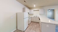 Located at 649 Creek Ridge Rd in Greensboro, NC, this single-floor residence offers a practical and comfortable layout across a compact, efficient footprint. The open-concept kitchen is a functional highlight, featuring white cabinetry, a full suite of white appliances including a refrigerator and electric range, a stainless steel sink, and a light-toned stone countertop that extends into a breakfast bar — ideal for casual dining. Track lighting and a textured ceiling complete the kitchen's clean aesthetic. The living area flows naturally from the kitchen, benefiting from wood-look plank flooring and natural light from a large window. The bedroom is a well-sized retreat, carpeted for comfort, and equipped with a ceiling fan with light fixture, a large window with blinds for natural light and privacy, and access to a closet. The full bathroom includes a tub-shower combination, a white vanity with storage, a wall mirror, and Hollywood-style lighting. A dedicated laundry room provides added convenience, featuring washer/dryer hookups, wire shelving for storage, and an in-unit water heater. Throughout the space, neutral wall tones, light flooring, and consistent trim create a cohesive, move-in ready atmosphere.