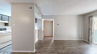 This single-story, 1-bedroom, 1-bathroom residence offers a thoughtfully arranged floor plan that maximizes every square foot of its compact footprint. Wood-style plank flooring runs consistently throughout, providing a cohesive and modern aesthetic, while textured ceilings add a classic touch to each room.

The living room serves as the focal point of the home, anchored by a classic brick fireplace and illuminated by natural light streaming through a sliding glass door that opens to an outdoor balcony area. Adjacent to the living room, a dedicated dining area and a galley-style kitchen offer a functional layout. The kitchen features dark cabinetry, white countertops, and ample storage on both sides, accommodating a full suite of appliances including a range, refrigerator, and dishwasher.

The bedroom is a comfortable, well-lit retreat with a ceiling fan, a window with outdoor views, and access to a spacious walk-in closet equipped with dual wire shelving systems for organized storage. The bathroom includes a wide vanity with a marble-style countertop, dark cabinetry, a large mirror, and wood-style flooring that ties seamlessly into the rest of the home. A hallway connects the private areas of the residence, completing this efficient and inviting layout.