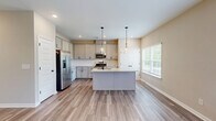 This well-appointed two-story home in Cartersville, Georgia offers a thoughtfully designed layout spread across two floors. The main level features an open-concept kitchen and living area, where light wood-look tile flooring flows seamlessly throughout. The kitchen stands out with granite countertops, gray shaker-style cabinetry with matte black hardware, stainless steel appliances including a gas range and French door refrigerator, and a center island with pendant lighting. The living room is bright and airy, featuring a ceiling fan, French doors that invite natural light, and views of the outdoors. An attached garage with a dedicated opener system provides convenient access. Upstairs, three bedrooms are finished with plush neutral carpeting and windows that bring in natural light. The generously sized primary bedroom offers a comfortable retreat. Three full bathrooms are distributed across the home, each featuring wood-look tile floors, gray vanity cabinetry, and clean white fixtures. Secondary bathrooms include a tub-shower combination, while another features a streamlined vanity layout. Neutral warm-toned walls throughout the home create a cohesive, move-in-ready atmosphere well suited for everyday living.