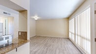 Located at 2901 Euclid Ave NE in Albuquerque, New Mexico, this single-story, two-bedroom, two-bathroom residence offers a well-organized and functional layout with consistent light wood-style flooring throughout. The living room is bright and open, anchored by large sliding glass doors fitted with vertical blinds that invite abundant natural light and provide direct access to an outdoor patio area with views of surrounding greenery.

The kitchen is a standout feature, boasting rich dark wood cabinetry, granite countertops, a tile backsplash, and a full suite of stainless steel appliances including a refrigerator, dishwasher, and electric range. A pass-through breakfast bar connects the kitchen to the living area, enhancing the sense of openness.

The primary bedroom is generously sized and includes mirrored sliding closet doors and its own sliding glass door leading to an outdoor space. The second bedroom is well-proportioned, featuring a large window with outdoor views and a ceiling-mounted light fixture. Both rooms share the same warm neutral tones that carry throughout the space.

The bathrooms are cleanly appointed, with one featuring a full tub-shower combination with floor-to-ceiling tile surround and wood-style flooring. The overall ambiance is clean, neutral, and move-in ready.