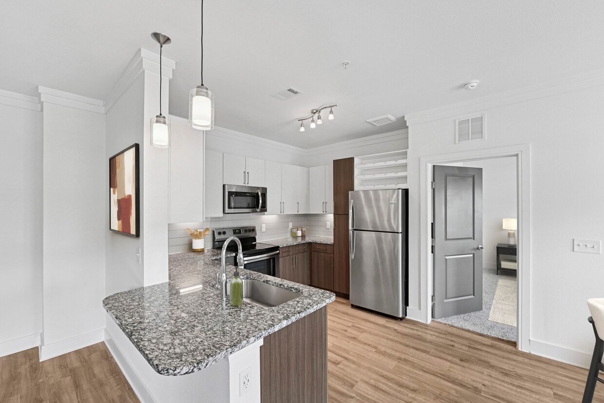 Kitchen with white and espresso cabinetry, speckled granite countertops, stainless steel appliances, and hard surface flooring - Avalon Frisco