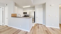 Located at 21311 Alder Dr in Santa Clarita, CA, this single-story 2-bedroom, 2-bathroom home offers a clean, modern aesthetic throughout. The living area stands out with impressively tall ceilings, light wood laminate flooring, and an abundance of natural light streaming through vertical-blind-covered windows and a sliding glass door that opens to an outdoor patio. A transom window above the entry door adds additional brightness to the welcoming entryway.

The kitchen features a peninsula with a dark quartz-style countertop, white cabinetry, stainless steel appliances including a gas range, microwave, and refrigerator, and light tile flooring—offering both style and functionality. The space flows naturally into the living and dining areas.

Both bedrooms continue the light wood flooring theme, with soft neutral wall tones and windows fitted with vertical blinds that allow for flexible natural light. The primary bedroom provides a comfortable, well-proportioned retreat. A dedicated closet offers organized storage.

The two bathrooms are finished with white tile flooring, white cabinetry with dark countertops, and full tub-shower combinations, maintaining a consistent, clean aesthetic. Overall, this home presents a bright, modern, and functional living environment well-suited to its sunny Southern California setting.