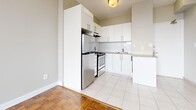 Located at 200 Dufferin Street in Toronto's vibrant West End, this one-bedroom, one-bathroom unit offers an efficient and thoughtfully laid-out living space across a single floor. The open-concept kitchen and living area form the heart of the unit, where white large-format ceramic tiles in the kitchen transition seamlessly into warm parquet wood flooring in the living area. The kitchen is well-appointed with white cabinetry, a subway tile backsplash, granite countertops, and stainless steel appliances including a refrigerator and electric range — providing both style and functionality. A breakfast bar peninsula adds casual dining convenience. The living area is bright and airy, benefiting from a large window and access to a balcony that brings in natural light and city views. The bedroom is a comfortable and serene retreat, featuring the same classic parquet flooring, soft neutral walls, a window with urban views, a built-in closet, and baseboard heating. The bathroom is clean and simply finished, with white tile surrounding a full soaker tub and a pedestal sink. Throughout the unit, neutral tones and consistent finishes create a cohesive, practical living environment well-suited to urban living in one of Toronto's most connected neighbourhoods.