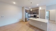 Located at 1820 Gold Hill Rd in Fort Mill, SC, this single-floor residence offers a thoughtfully designed layout with a clean, contemporary aesthetic throughout. The open-concept kitchen and living area serve as the heart of the home, where light wood-look flooring, a ceiling fan, and abundant natural light create a welcoming atmosphere. The kitchen is well-equipped with dark espresso cabinetry, a white quartz countertop, a subway tile backsplash, stainless steel appliances including a refrigerator, range, and built-in microwave, and a peninsula with a double-basin sink — ideal for both cooking and entertaining. Pendant lighting above the peninsula adds a stylish finishing touch. The bedrooms feature plush wall-to-wall carpeting, ceiling fans with lighting, and windows with blinds that invite natural light while maintaining privacy. The bathrooms are finished with hexagonal tile flooring, dark vanity cabinetry, white quartz countertops, and brushed nickel hardware. One bathroom includes a spacious walk-in shower with a sleek frameless glass sliding door, while another offers accessibility-friendly grab bars. The overall design is neutral and modern, providing a versatile canvas throughout.