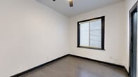 Located at 5849 Sunset Boulevard in the heart of Hollywood, Los Angeles, this compact studio unit offers a well-designed single-level layout that makes efficient use of its intimate footprint. The main living area features rich, dark hardwood-style flooring that extends throughout, complemented by crisp white walls and bold black door and baseboard trim that lend a clean, modern contrast to the space.

A kitchenette is tucked along one wall, outfitted with white shaker-style cabinetry, dark countertops, a mosaic tile backsplash, and a compact refrigerator — providing essential functionality within a minimal footprint. Two interior doors lead from the main area: one serving as the unit's entrance and the other providing access to the bathroom.

The bathroom is appointed with marble-look tile flooring, a pedestal sink with chrome fixtures, a wall-mounted medicine cabinet with mirror, and a toilet — all finished in a clean, white palette that maximizes the sense of space.

A window fitted with horizontal blinds allows natural light to filter into the living area, brightening the white walls and adding an airy quality to the space. The ceiling fan visible in the scan view adds a practical comfort element. This unit is ideally situated for those seeking a streamlined, low-maintenance space in one of Los Angeles' most iconic and centrally located neighborhoods.