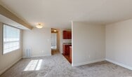 This single-floor residence offers a thoughtfully arranged layout that balances comfort and functionality throughout. The living area is generously sized, featuring soft wall-to-wall carpeting that adds warmth underfoot. Multiple windows fitted with blinds allow natural light to fill the space, creating a bright and inviting atmosphere. A flush-mount ceiling light provides additional illumination, and a baseboard heating unit ensures year-round comfort.

The galley-style kitchen is efficiently designed, with rich cherry-toned cabinetry lining both walls and offering ample upper and lower storage. Light granite-style countertops provide a clean contrast to the warm wood tones, while stainless steel appliances — including a gas range and a full-size refrigerator — complete the well-equipped cooking space. Hardwood-style flooring runs throughout the kitchen, adding a polished finish.

A hallway connects the living area to the bedroom and bathroom. The bedroom is a comfortable, carpeted retreat with multiple windows that invite natural light. The full bathroom is clean and functional, featuring a tub and shower combination with brushed nickel fixtures, a white vanity with countertop basin, and a dark-framed mirror above. The overall aesthetic throughout the residence is neutral and move-in ready, with a cohesive palette of warm beige tones and classic finishes.