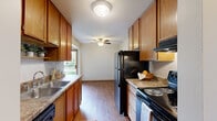 Located at 8015 36th Ave N in New Hope, Minnesota, this 2-bedroom, 1-bathroom single-floor unit offers a practical and comfortable layout across a compact, efficiently arranged floor plan. The galley-style kitchen is well-appointed with warm wood cabinetry, granite-look countertops, hardwood-style flooring, and black appliances including a refrigerator and range, complemented by a stainless steel sink. A ceiling fan overhead and a window overlooking the balcony bring natural light and airflow into the space. The kitchen opens toward the dining area, which transitions seamlessly into the living room. The living room features plush carpet, a ceiling fan, and a sliding glass door leading to a private balcony with outdoor views — an inviting feature for relaxing or entertaining. Both bedrooms are carpeted and equipped with ceiling fans and baseboard heating. The primary bedroom offers generous closet space with built-in shelving and wire racks, providing ample storage. The second bedroom includes a window with natural light. The full bathroom is clean and functional, featuring white tile, a tub/shower combination, and mosaic tile flooring. Hallways connect the rooms efficiently throughout the unit, making navigation intuitive. Baseboard heating is present throughout, ensuring consistent warmth during Minnesota winters.