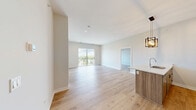 Located at 440 Green Bay Rd in Highwood, IL, this thoughtfully designed 2-bedroom, 2-bathroom residence offers a clean, contemporary aesthetic across a well-proportioned single-floor layout. Light hardwood flooring flows consistently throughout, complementing the neutral palette of soft white and warm greige walls that define the interior.

The open-concept kitchen and living area serves as the heart of the home. The kitchen features a large waterfall-edge island with an integrated sink, two-tone cabinetry combining crisp white uppers with warm wood-grain lowers, white subway tile backsplash, stainless steel appliances, and a striking industrial-style pendant light fixture. The living area extends naturally from the kitchen and opens directly to a private balcony via sliding glass doors, offering expansive elevated views of the surrounding Highwood neighborhood and treetop canopy.

The primary bedroom is generously sized, bathed in natural light through a large picture window overlooking lush greenery. Both bedrooms feature the same hardwood flooring and clean lines carried throughout the unit. The two full bathrooms are finished with floor-to-ceiling white tile surrounds, soaking tub-shower combinations, tile flooring, and matte black hardware accents. A dedicated closet and convenient layout round out this well-appointed residence.