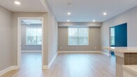 Located at 136 Stevens Ave in Little Falls, NJ, this single-floor unit presents a clean, contemporary aesthetic defined by light hardwood flooring, neutral wall tones, and recessed lighting throughout. The open-concept layout creates a seamless flow between the living and kitchen areas, making the space feel airy and versatile.

The kitchen is a standout feature, showcasing white shaker-style cabinetry with matte black hardware, light quartz countertops, and a herringbone-patterned gray tile backsplash. Stainless steel appliances, including a gas range, over-the-range microwave, and refrigerator, complement the modern design. A peninsula with pendant lighting provides additional workspace and serves as a natural divider between the kitchen and living area.

The living space is generously proportioned, featuring multiple windows with blinds that invite natural light while maintaining privacy. Additional rooms offer flexible use, each finished with the same light hardwood flooring and neutral walls. The bathroom is styled with a crisp black-and-white palette, featuring dark tile flooring, a white vanity with a black granite countertop, matte black fixtures, and a tiled shower-tub surround. The overall ambiance is fresh, modern, and move-in ready.