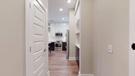 This well-designed 650 square foot apartment maximizes space efficiency with a thoughtful layout. The single-floor dwelling comprises one bedroom, one bathroom, and an open-concept kitchen and living area. The primary bedroom, measuring 120 square feet, offers a comfortable retreat.

The living area, as shown in the image, is a standout feature. It boasts a set of French doors with transom windows above, allowing abundant natural light to flood the space. These doors likely lead to an outdoor area, enhancing the indoor-outdoor flow. The room features warm, wood-look vinyl flooring that adds a touch of elegance and warmth to the space.

The walls are painted in a neutral beige tone, creating a bright and airy atmosphere. Recessed lighting in the ceiling provides even illumination throughout the room. The clean lines and modern finishes suggest a contemporary design aesthetic.

While not visible in the image, the apartment also includes a kitchen, bathroom, laundry area, and hallway. Given the compact size, these spaces are likely designed for maximum functionality. The open floor plan in the main living area helps to create a sense of spaciousness in this efficiently designed apartment.