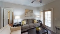 This single-floor residence showcases a cohesive modern design highlighted by rich hardwood flooring, soft gray walls, and crown molding throughout. The living room offers a comfortable, well-lit environment with ceiling fan, decorative wall art, and a glass door that invites natural light from outside. Adjacent to the living area, the dining space accommodates a round glass-top table beneath a track lighting fixture, complemented by a framed wall mirror that enhances the sense of depth.

The kitchen is well-appointed with dark espresso cabinetry, granite-style countertops, stainless steel appliances including a range and microwave, a central island for added workspace, and a pantry closet with louvered doors. Crown molding and recessed lighting add refined detail to the space.

The bedrooms are generously proportioned, each featuring hardwood floors, ceiling fans, and access to walk-in closets with built-in shelving. Natural light filters through windows dressed with sheer curtains and wood blinds.

The bathrooms are tastefully finished with dark wood vanities, granite countertops, and soaking tubs with tile surrounds. One bathroom features tall built-in cabinetry for ample storage, while both maintain a clean, contemporary aesthetic consistent with the rest of the home.